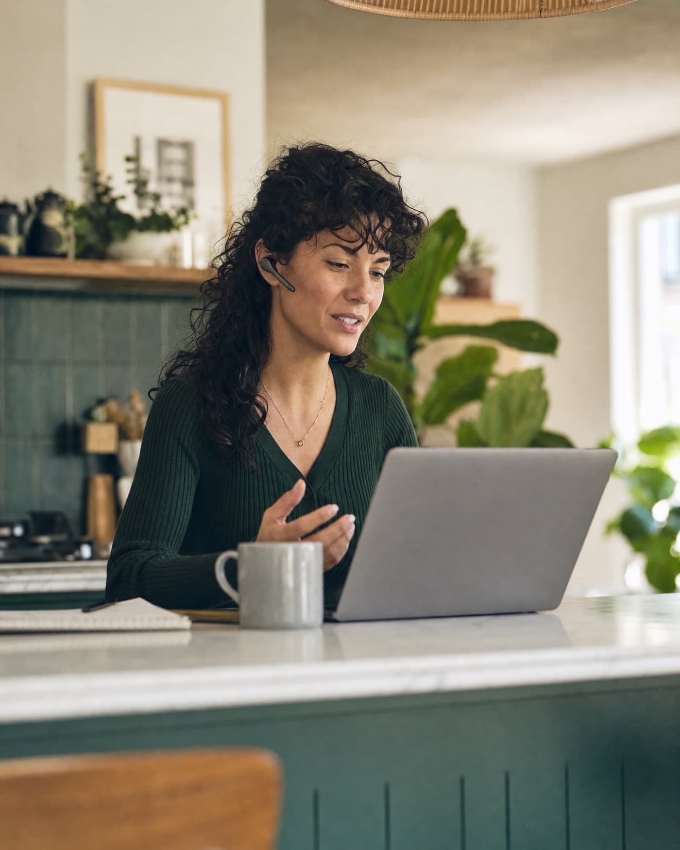 A woman on a call at her kitchen island, laptop open